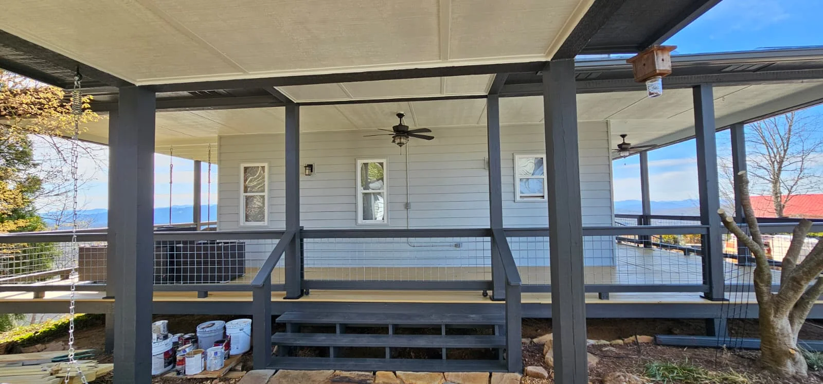 Screened porch with black frame windows, metal railing, and retractable awning system