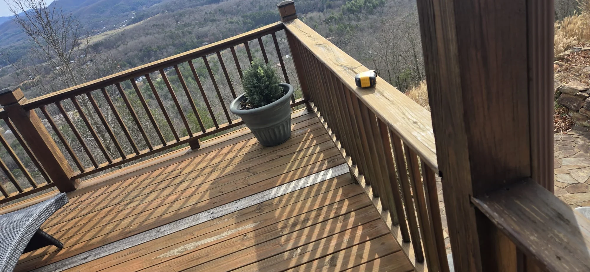 Wooden deck with metal railing overlooking forested mountain valley