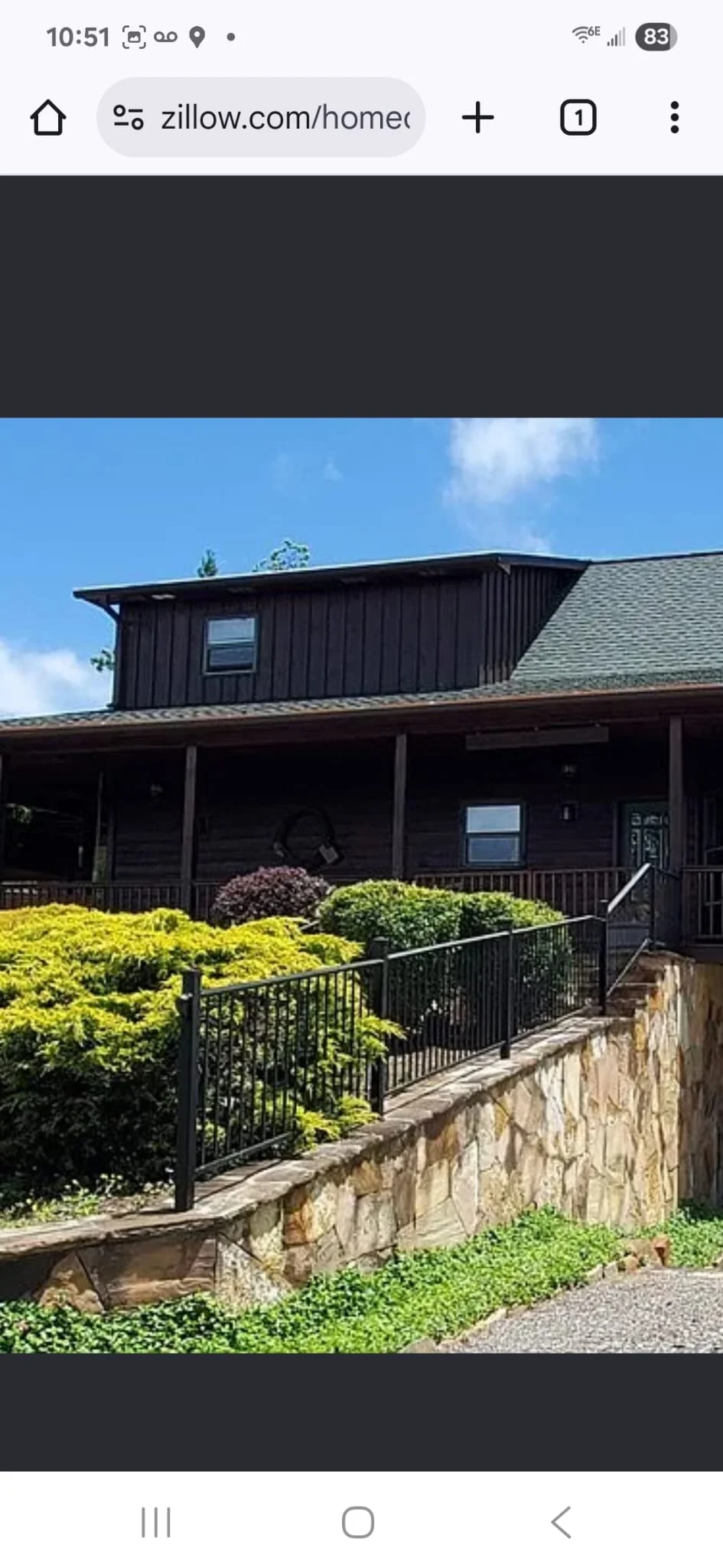 Black metal deck railing with vertical balusters installed on stone wall with landscaping