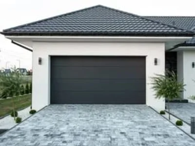 Dark gray modern garage door on white home with paved driveway
