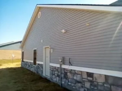 Home exterior with gray vinyl siding and stone veneer foundation detail