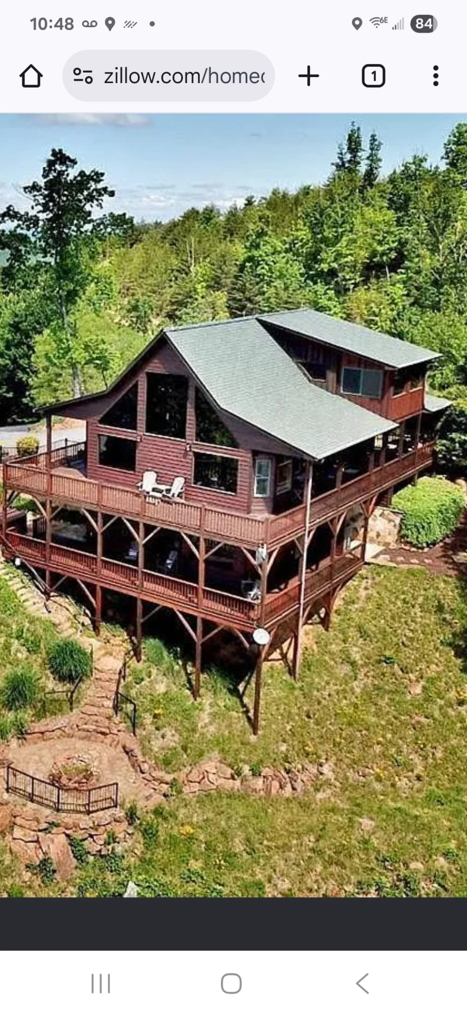 Elevated mountain home with new windows, cedar siding, and wraparound decks surrounded by forest