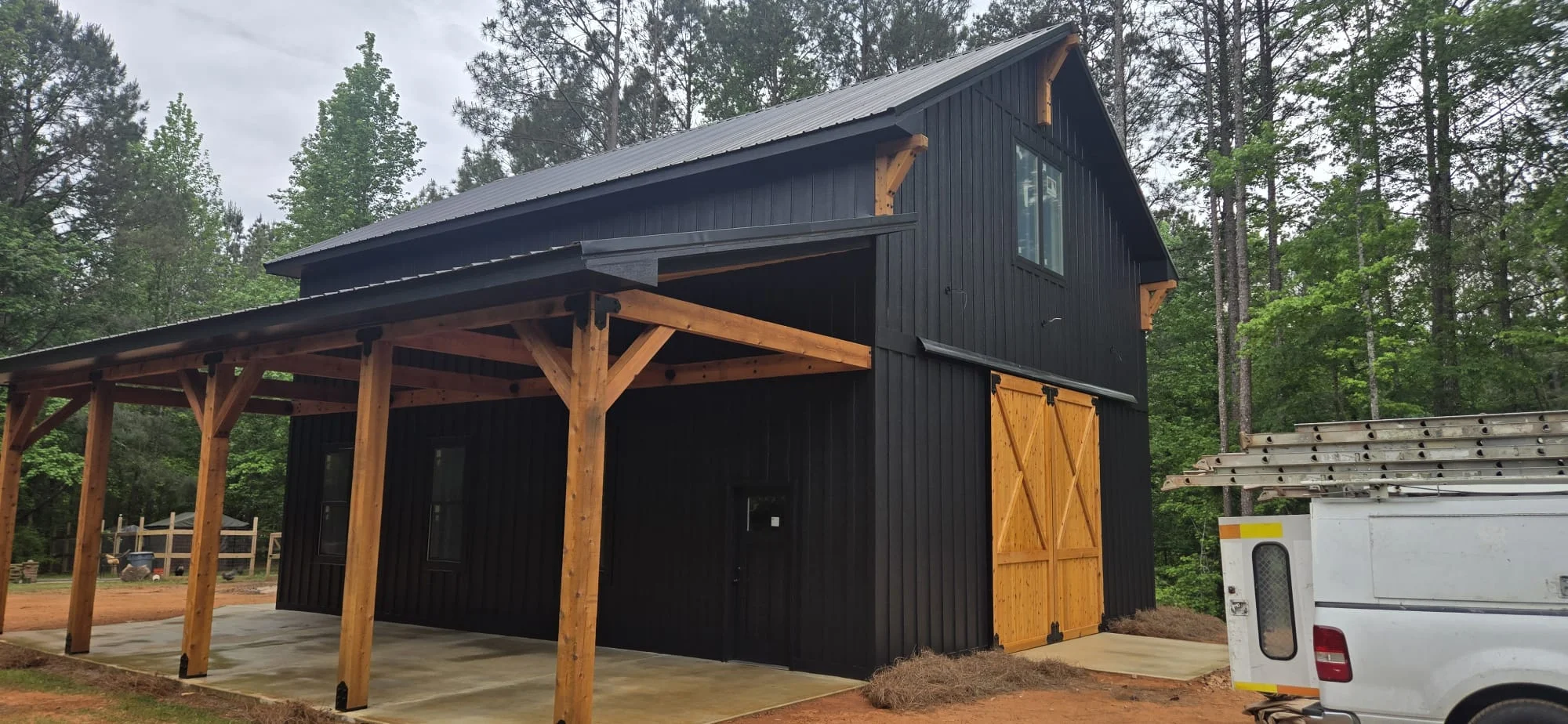 Black metal barn with wood beam carport and large fixed windows in Georgia