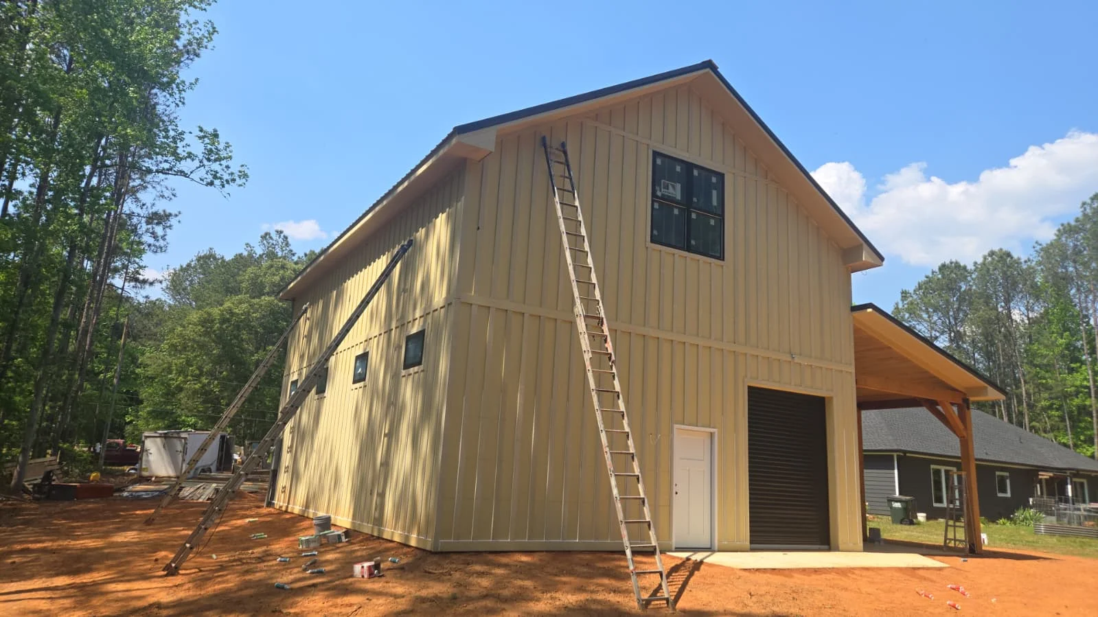 Tan metal building with black windows and covered porch during construction in Georgia