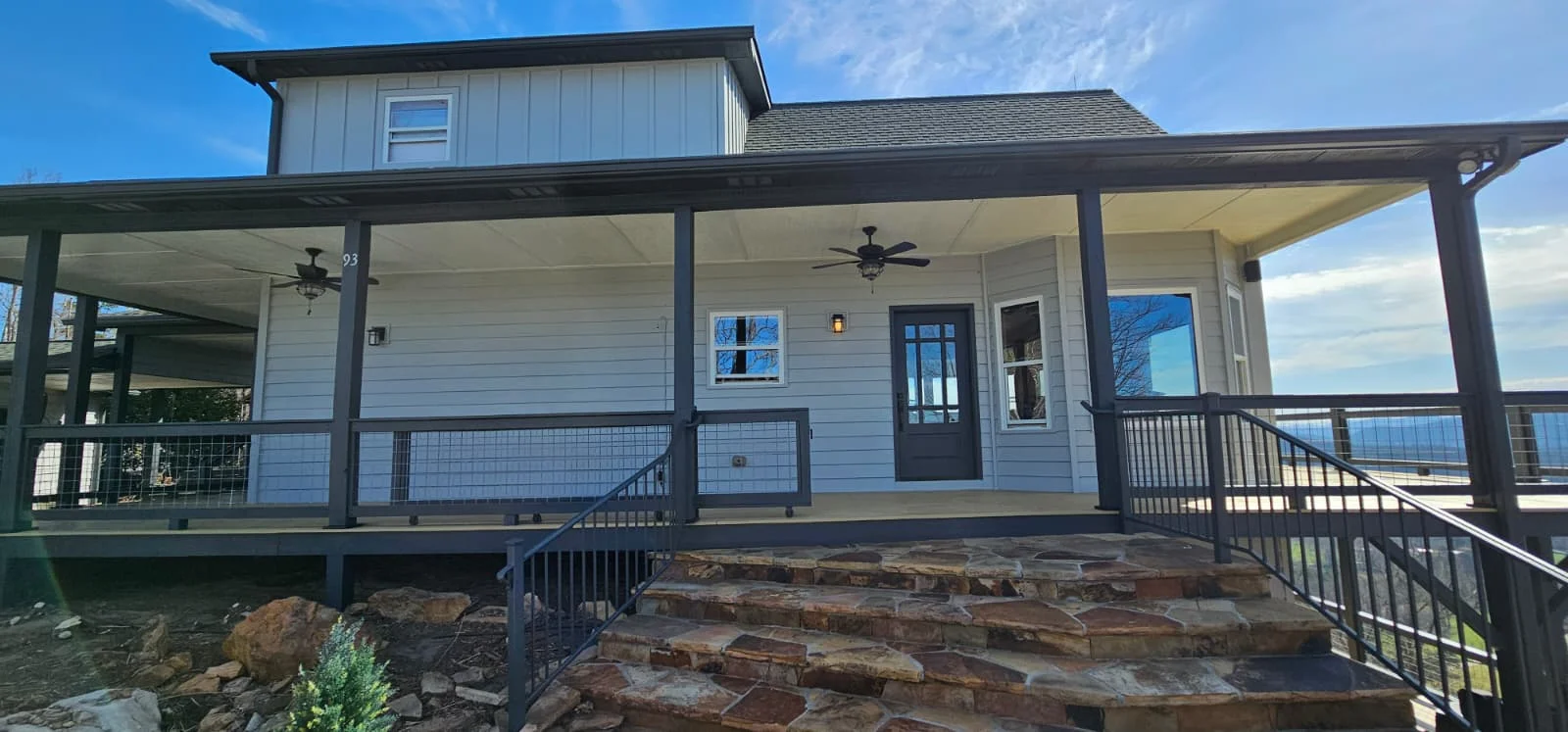 Modern farmhouse with new windows, glass doors, and metal pergola with cable railings