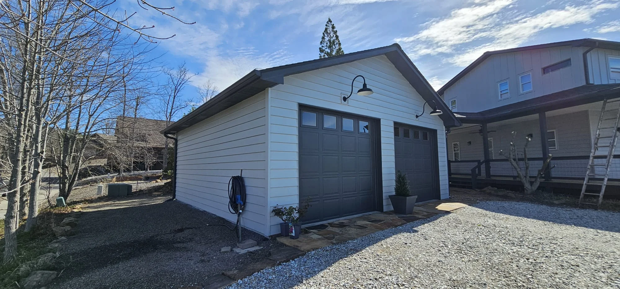 Modern white garage with black garage doors and window installation in residential setting