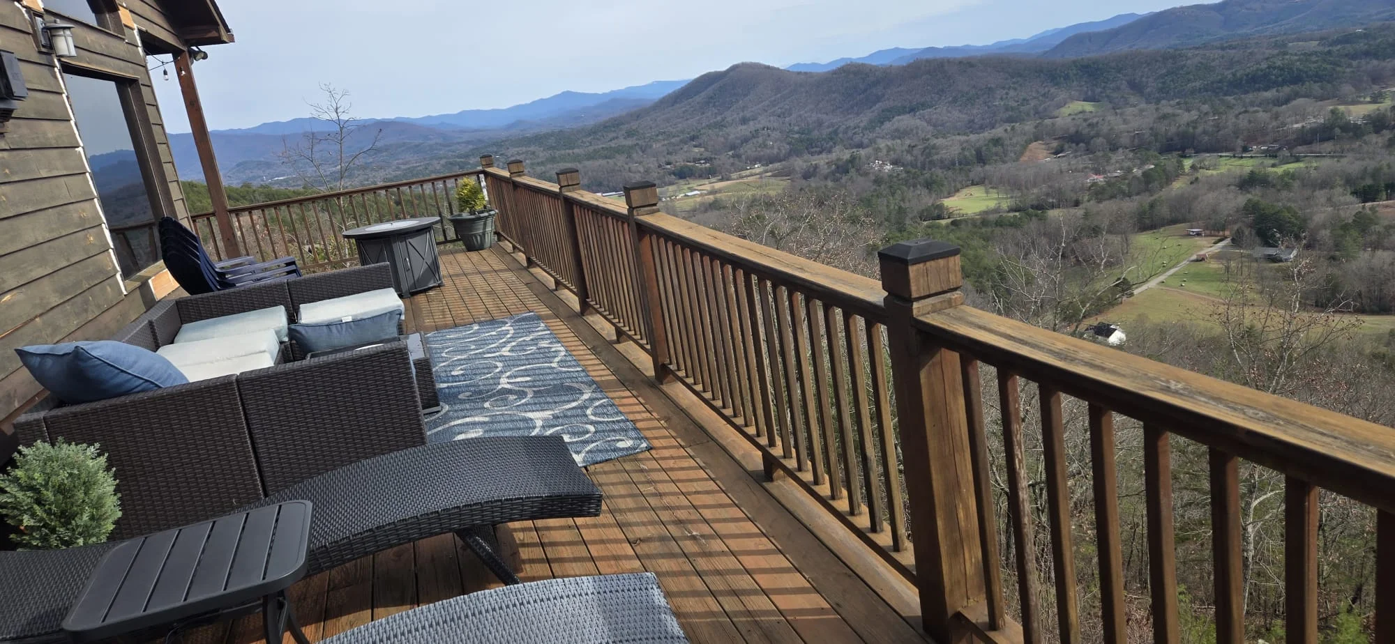 Elevated wooden deck with metal railings overlooking mountain valley landscape